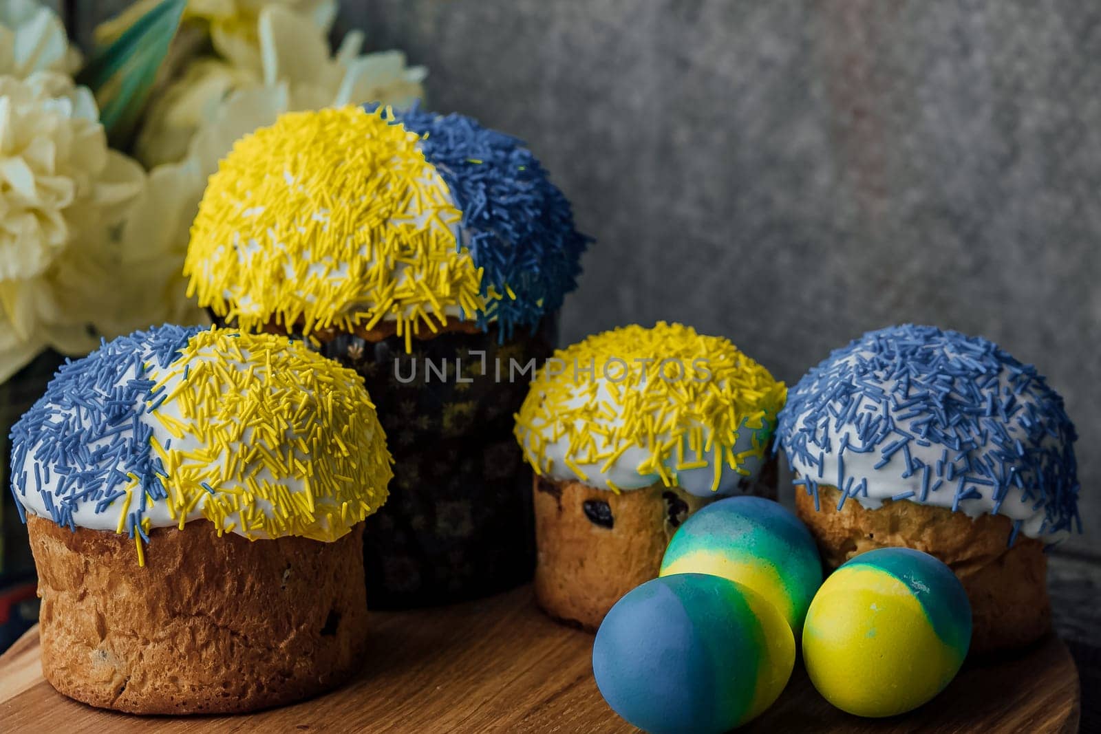 Delicious Easter cakes on a wooden table with flowers in the background. place for text. selective focus