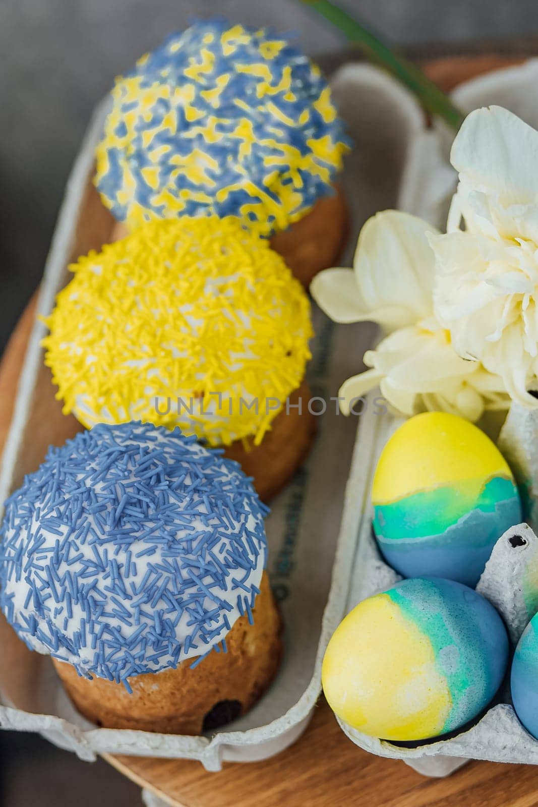 Easter cakes in the colors of the flag of Ukraine, yellow and blue in a cardboard stand with eggs, Easter eggs. place for text. selective focus.