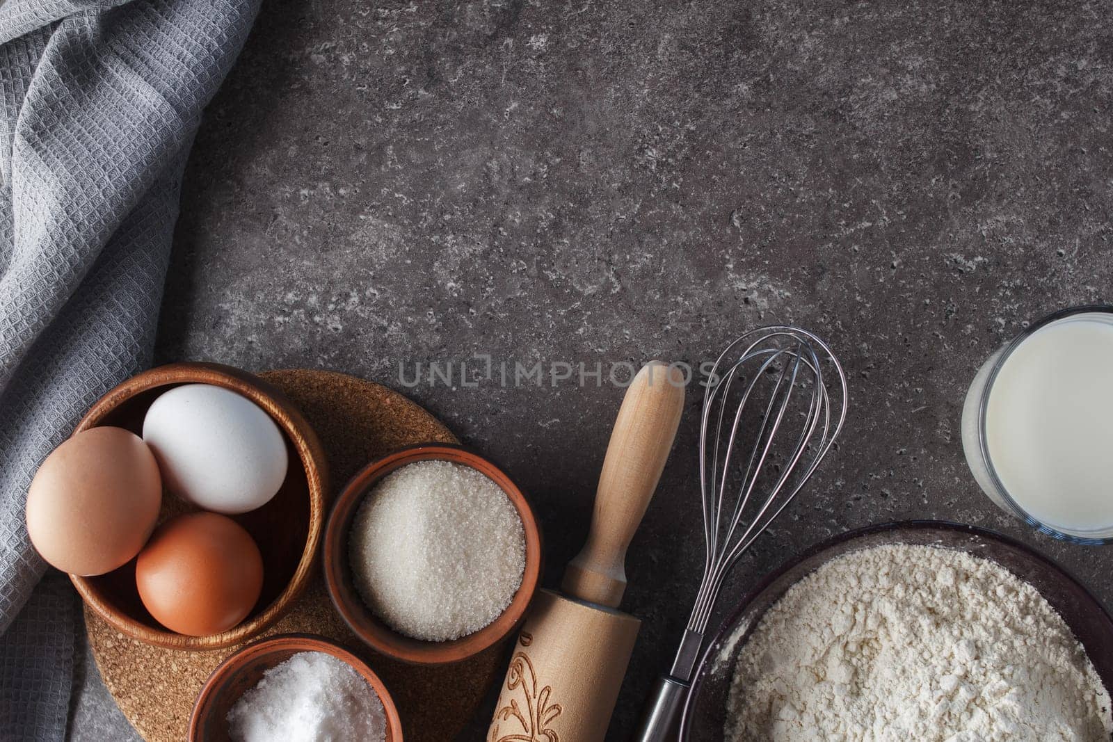 Preparation for baking. Eggs, sugar, milk, flour, salt, rolling pin, whisk on the kitchen table. copy space by lara29