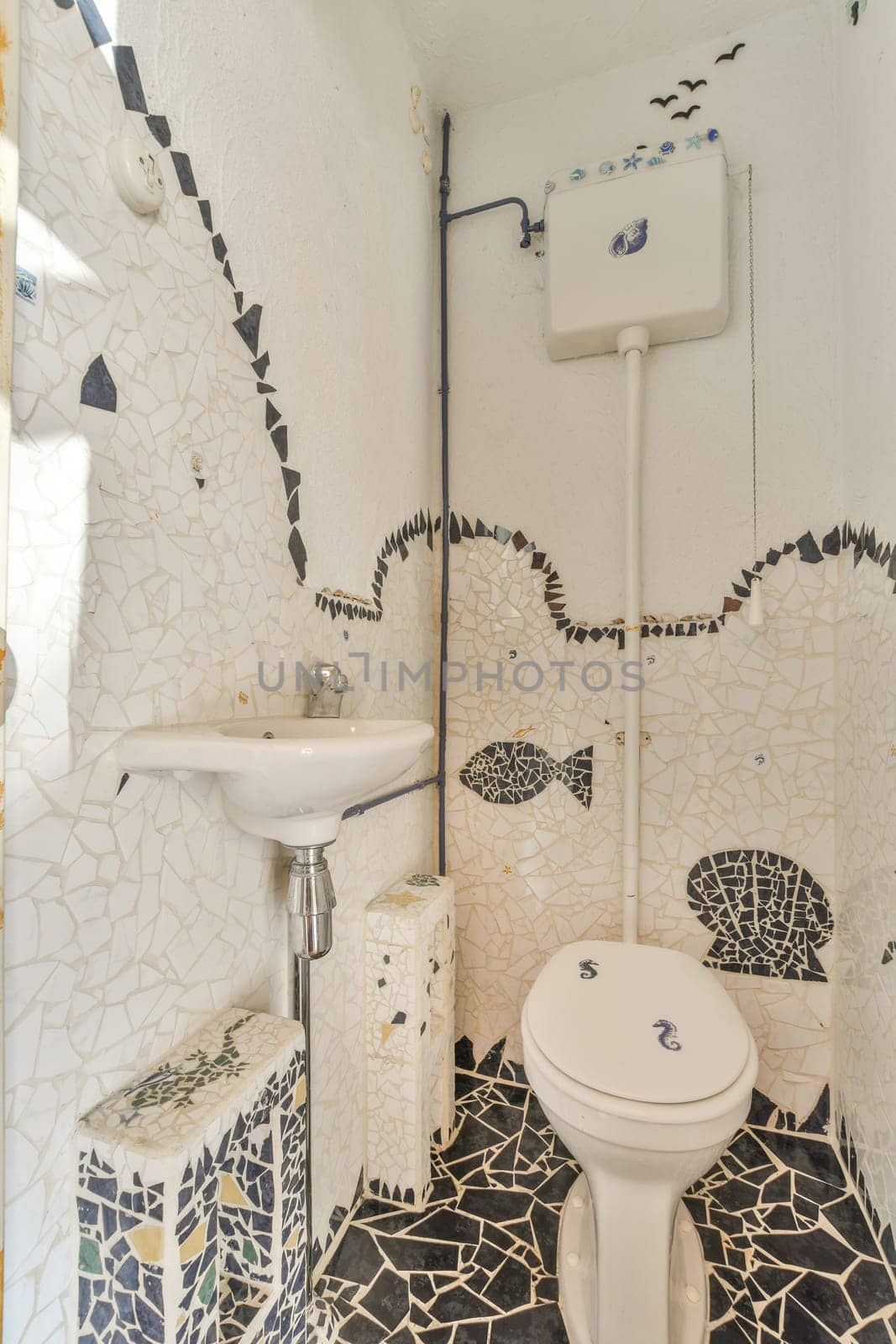 a bathroom with mosaic tiles on the walls and floor, including a toilet in the middle part of the room