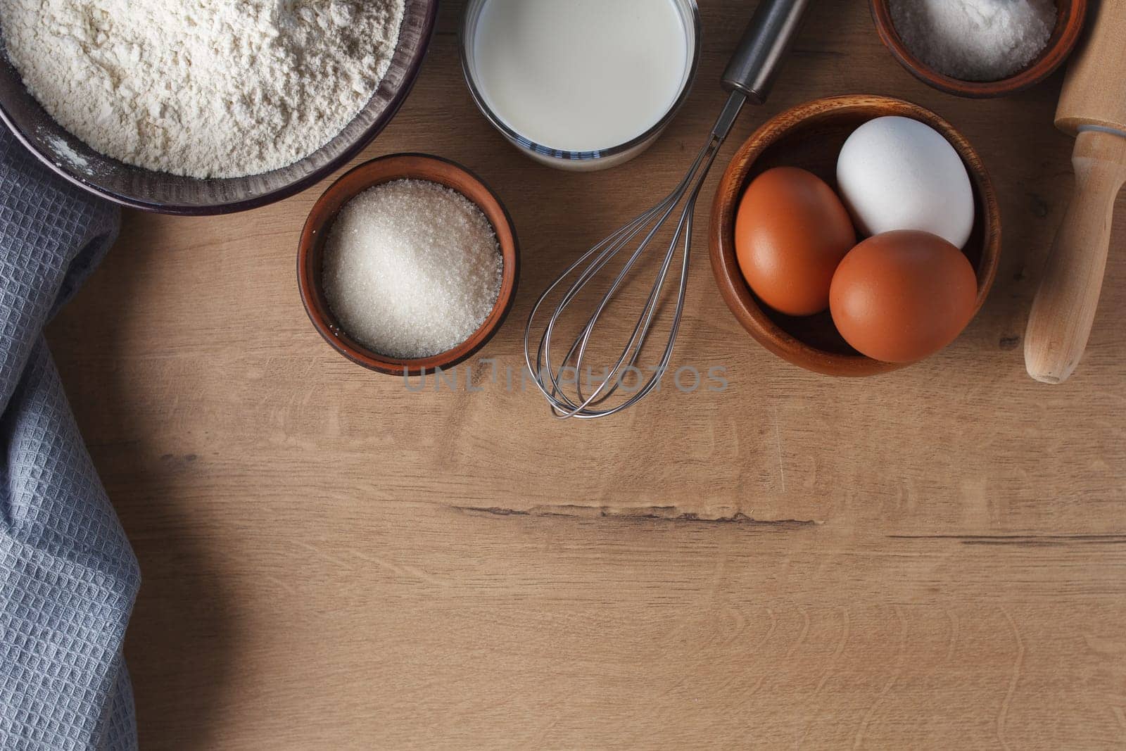 Preparation for baking. Eggs, sugar, milk, flour, salt, rolling pin, whisk on the kitchen table. copy space by lara29