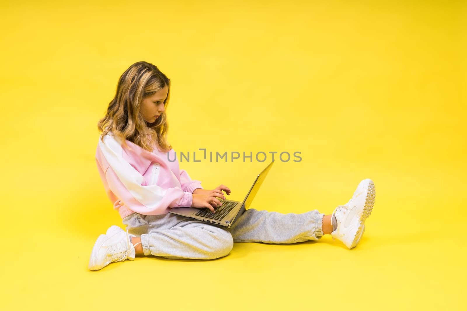 Little blonde kid girl on pastel yellow wall background. Childhood lifestyle concept. by Zelenin