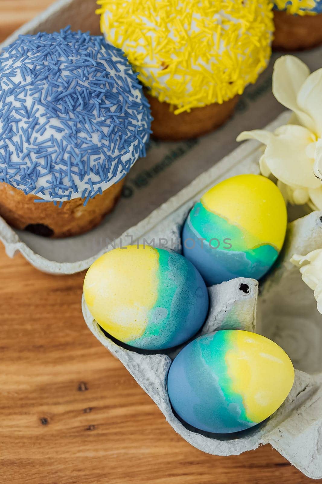 Easter cakes in the colors of the flag of Ukraine, yellow and blue in a cardboard stand with eggs, Easter eggs. place for text. selective focus.