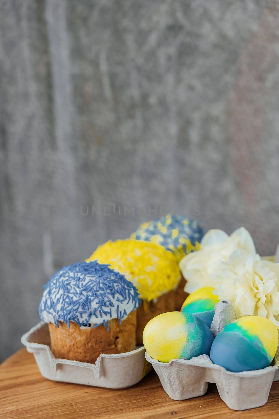 Easter cakes in the colors of the flag of Ukraine, yellow and blue in a cardboard stand with eggs, Easter eggs. place for text. selective focus.