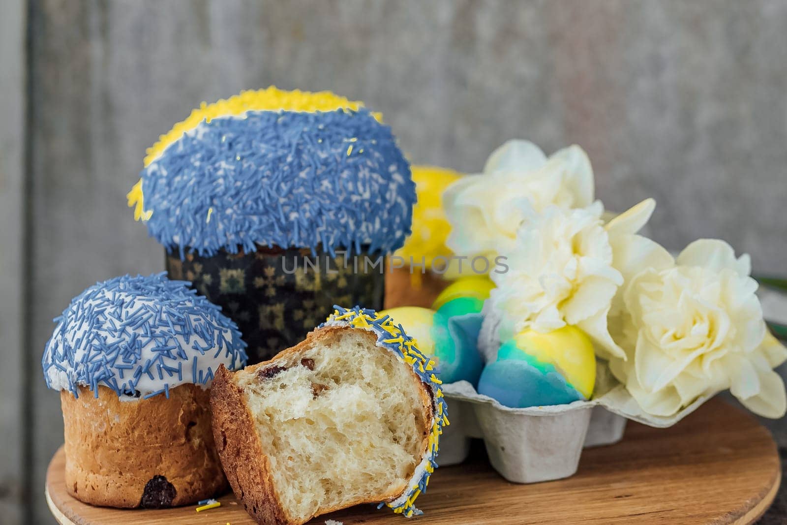 Easter cakes in the colors of the flag of Ukraine, yellow and blue in a cardboard stand with eggs, Easter eggs. place for text. selective focus.