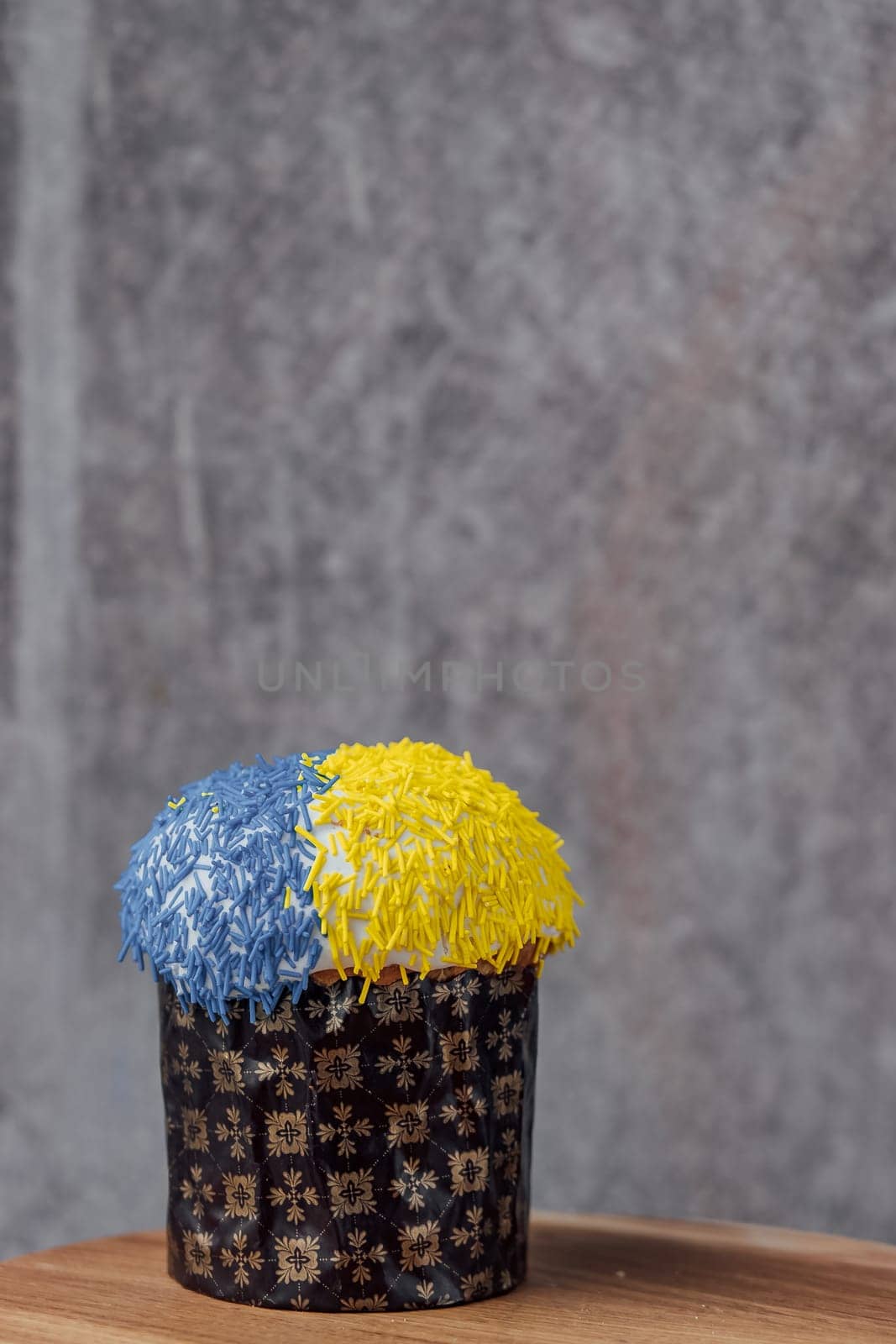 Easter cake is decorated with yellow-blue sprinkles on a gray background. place for text. patriotic paska in the color of the flag of Ukraine. Easter eggs