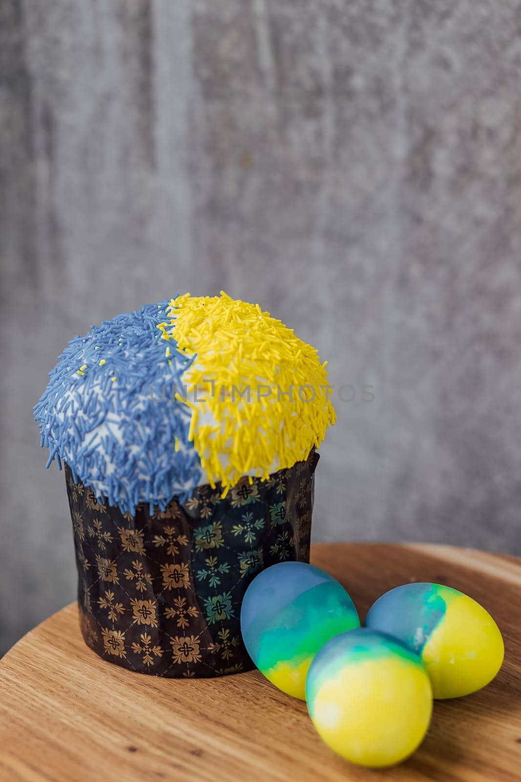 Easter cake is decorated with yellow-blue sprinkles on a gray background. place for text. patriotic paska in the color of the flag of Ukraine. Easter eggs.