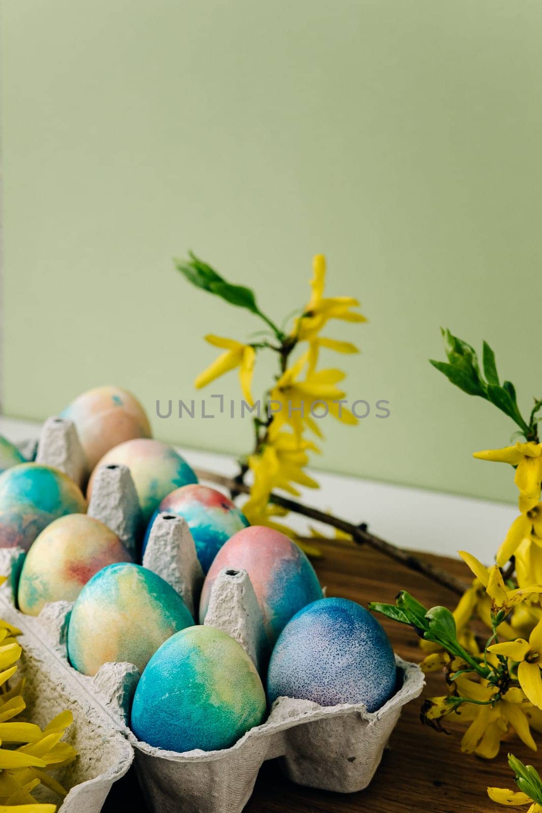 colorful Easter eggs on a green background next to yellow flowers