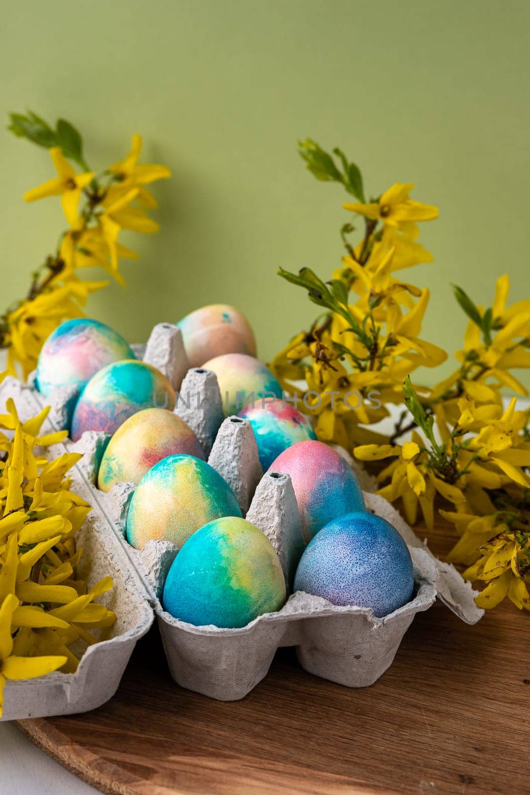 Happy Easter Easter eggs on rustic table with cherry blossoms. Natural dyed colorful eggs in paper tray on wooden board and spring flowers in rustic room. Moody atmospheric image