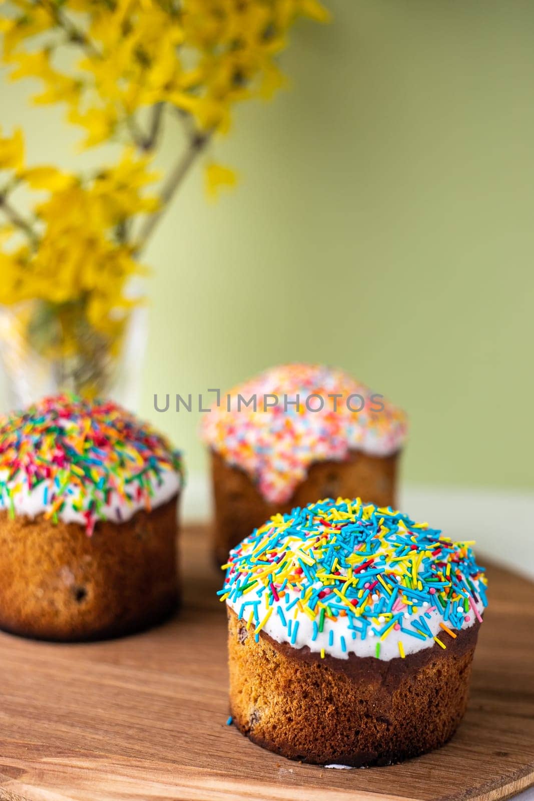 Easter composition with Easter cakes, wooden stand and spring flowers on a yellow background. copy space.