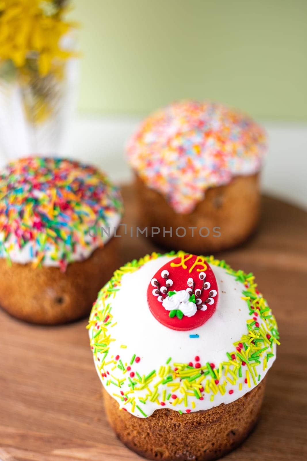 Easter composition with Easter cakes, wooden stand and spring flowers on a yellow background. copy space.