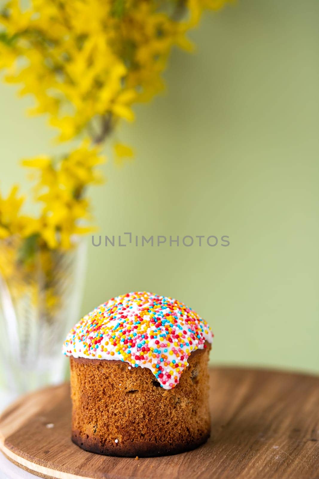 Easter cake with a bow on a yellow, light green background, and yellow spring flowers. Easter food. minimal concept.