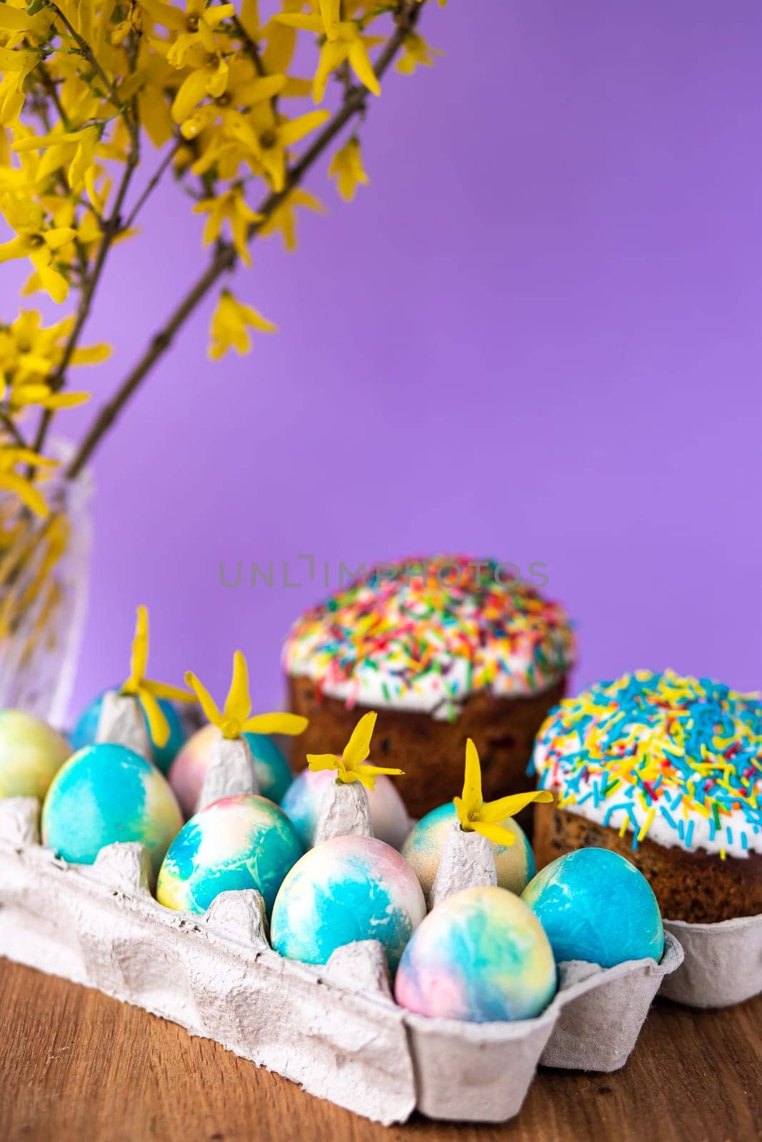 Easter cake on a purple background with yellow spring flowers. easter colored eggs. Easter food. minimal concept. by Anyatachka