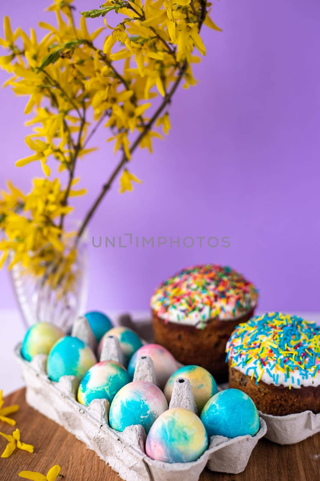 Easter cake on a purple background with yellow spring flowers. easter colored eggs. Easter food. minimal concept