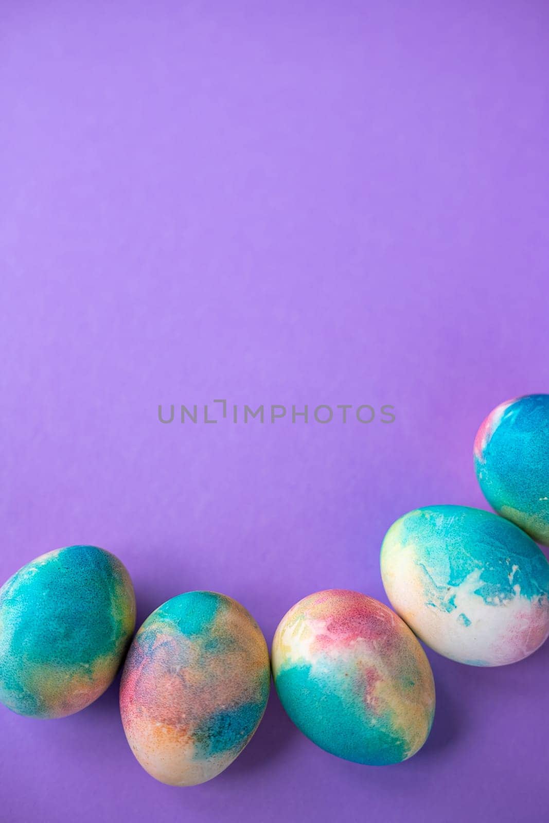 Easter composition with colorful eggs in shopping cart, wooden bunny and spring flowers on purple background. Banner. Copy space. by Anyatachka
