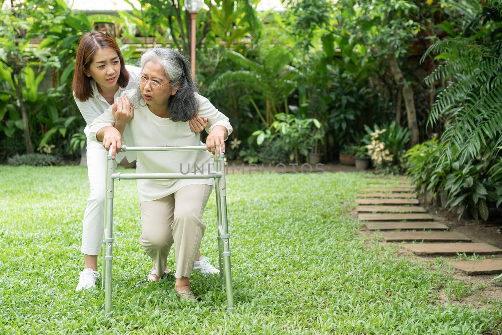 Asian senior woman falling down at home in the backyard caused by myasthenia (Muscle Weakness) and the daughter came to help support. Concept of old elderly insurance and health care