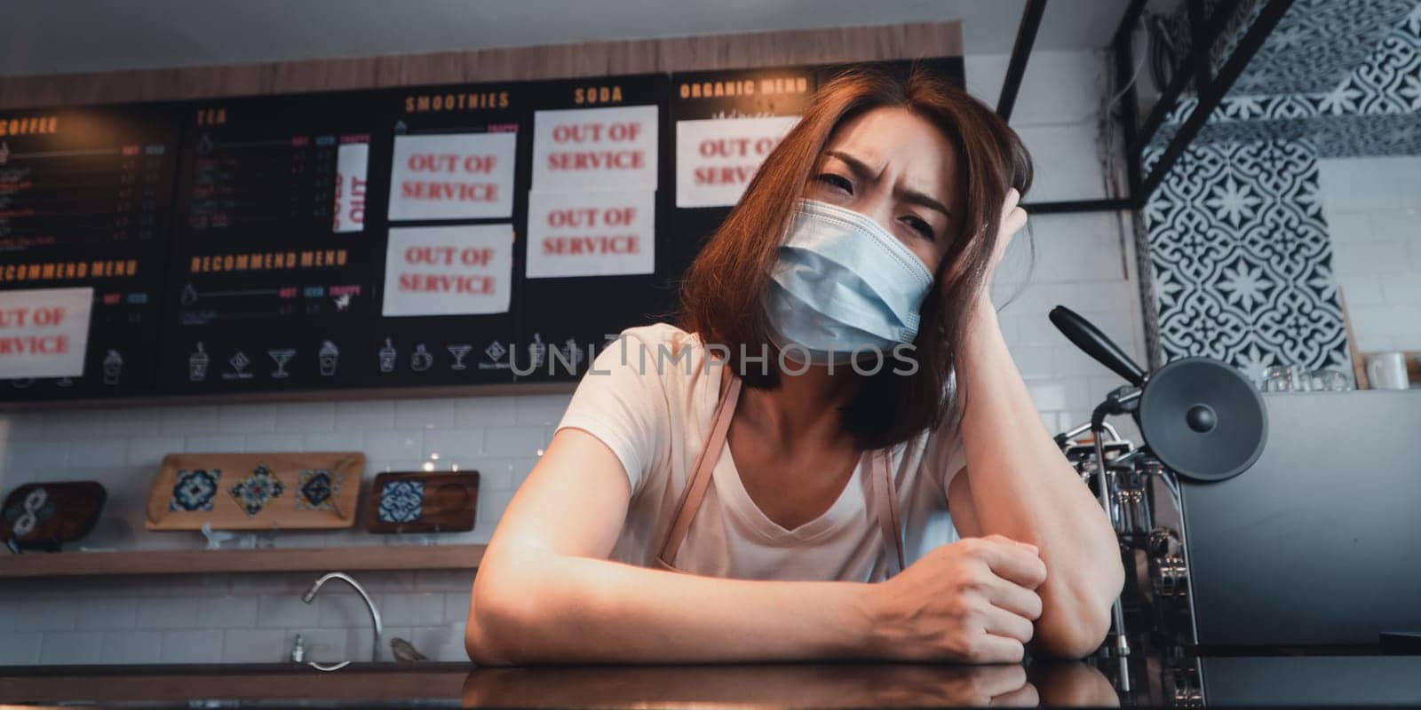 Asian woman coffee shop business owner Stressed and disappointed from The effects of the coronavirus pandemic resulting in business losses by PattyPhoto