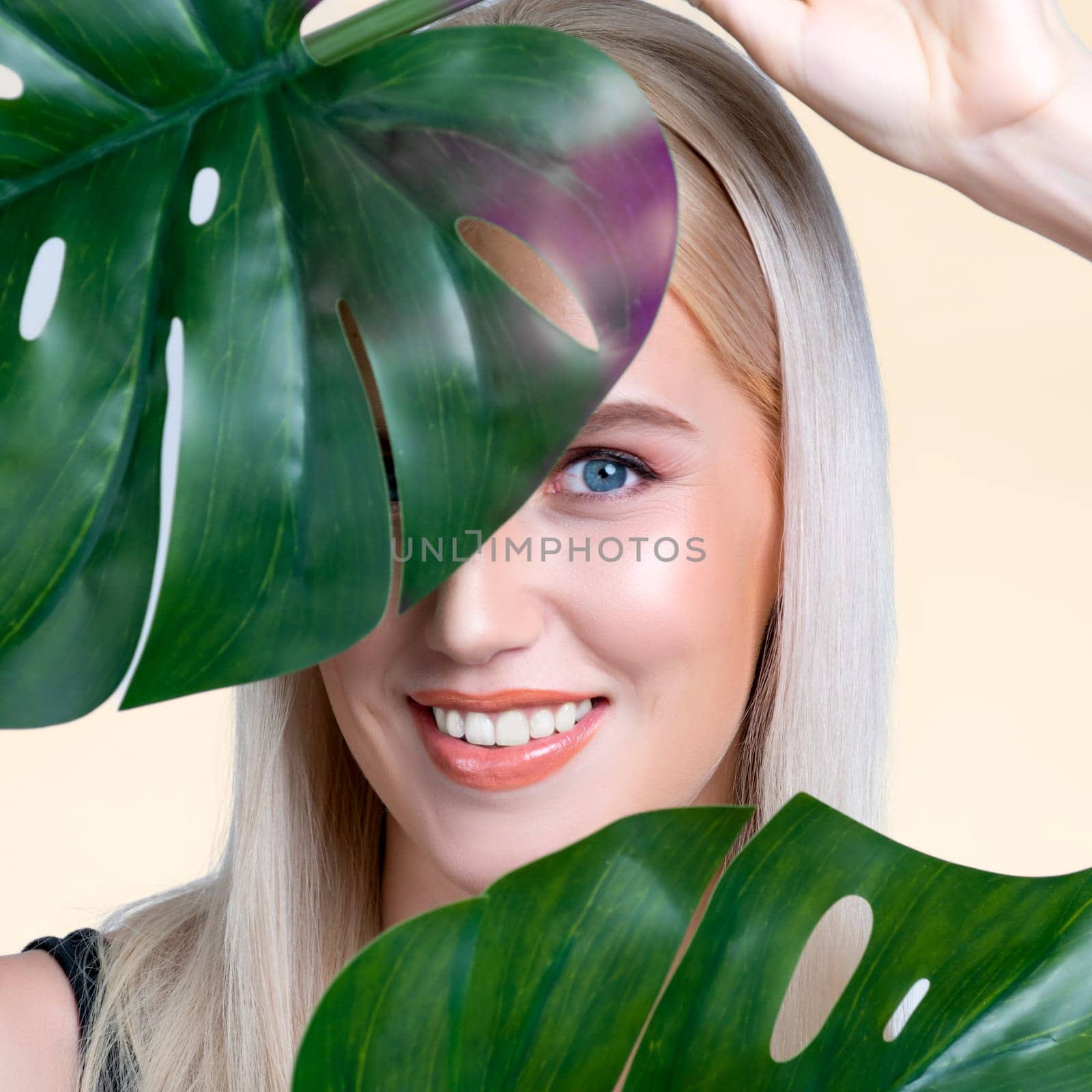 Closeup facial portrait personable woman holding green monstera. by biancoblue