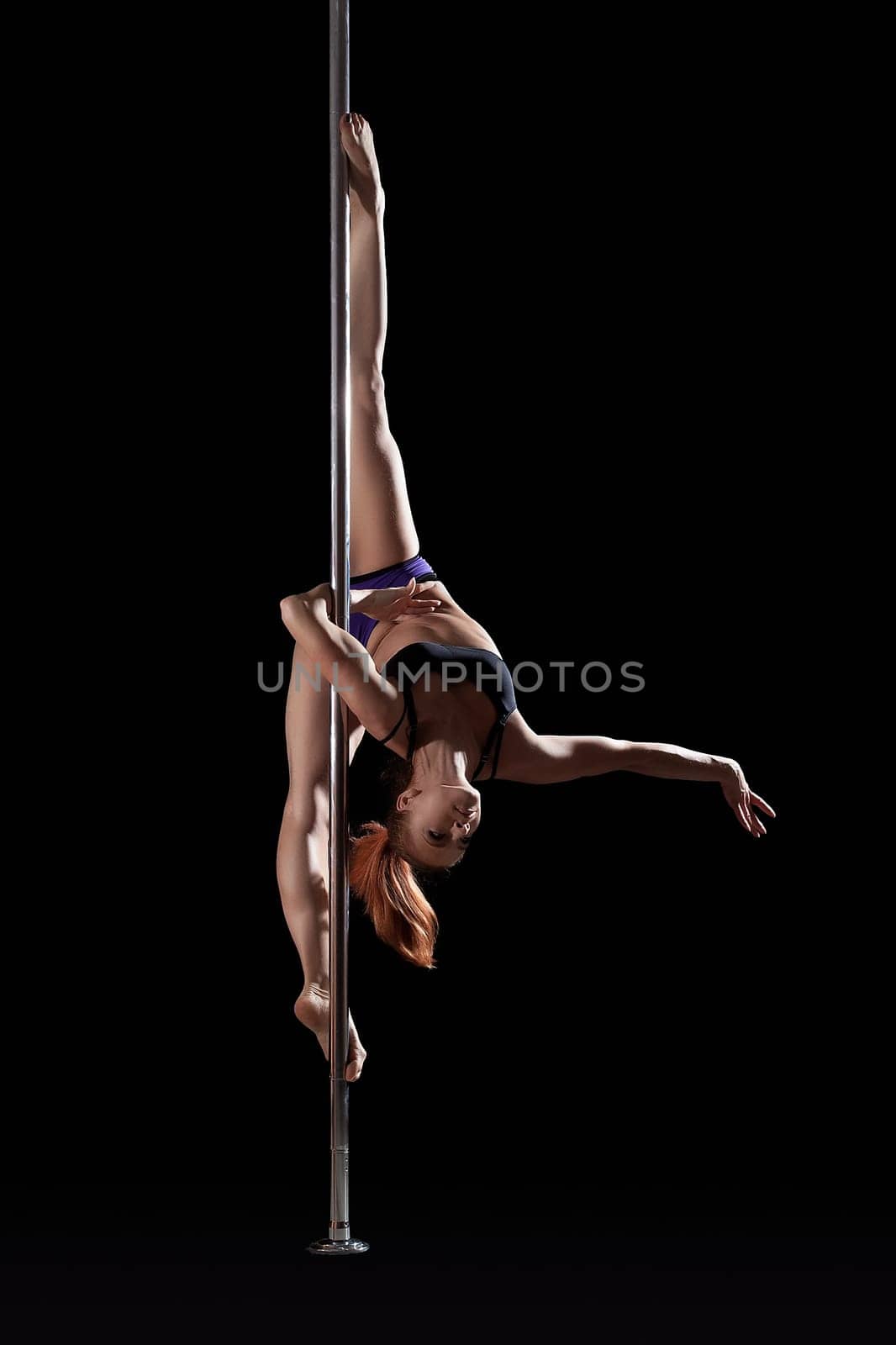 Flexible slim pole dancer posing on split, upside down