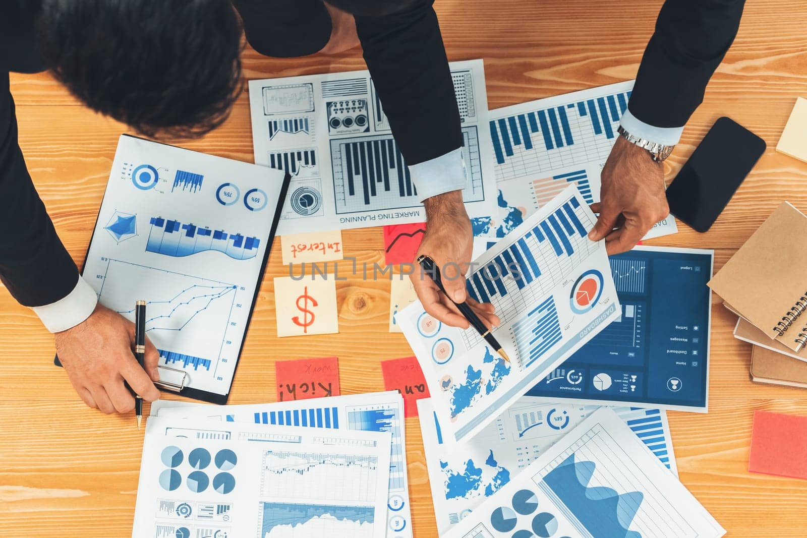 Top view analyst team discussing financial data on digital dashboard, analyzing chart and graph papers by data science software on wooden table background. Business intelligence and Fintech. Fervent