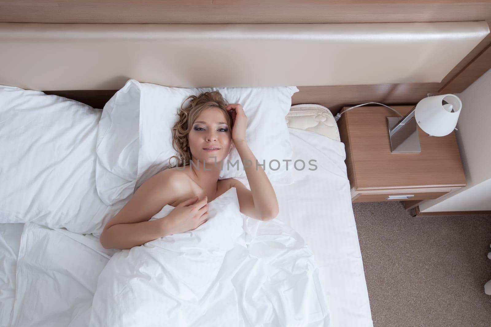 Image of smiling awakened girl lying in bed, close-up