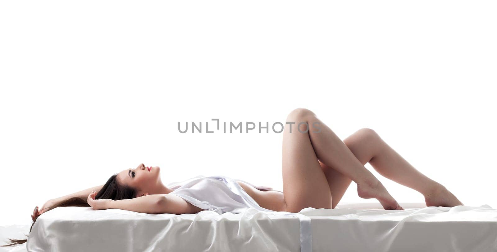 Profile of seductive young woman lying in bed, isolated on white
