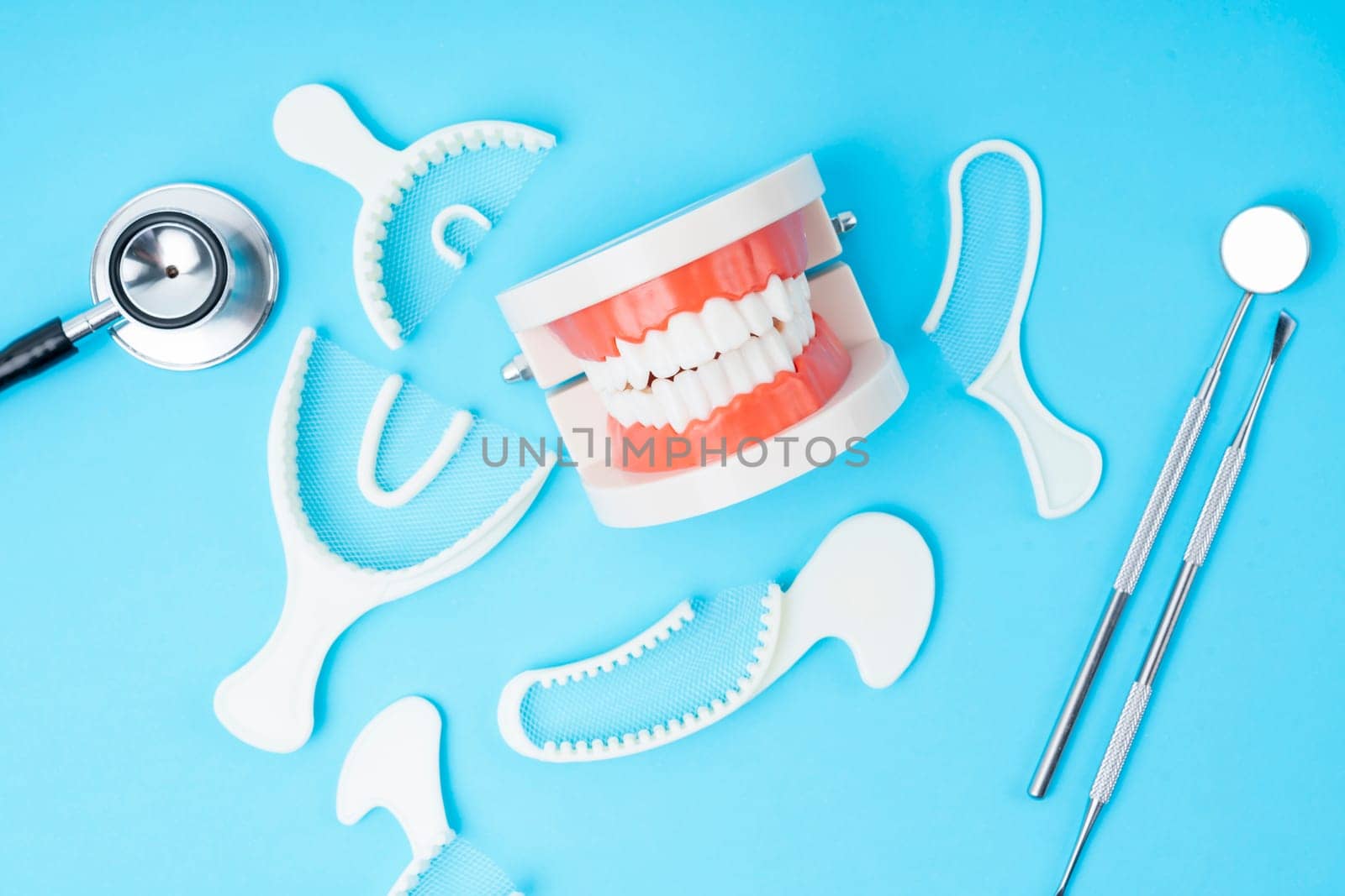 The Teeth model and instrument dental on blue background. by Gamjai