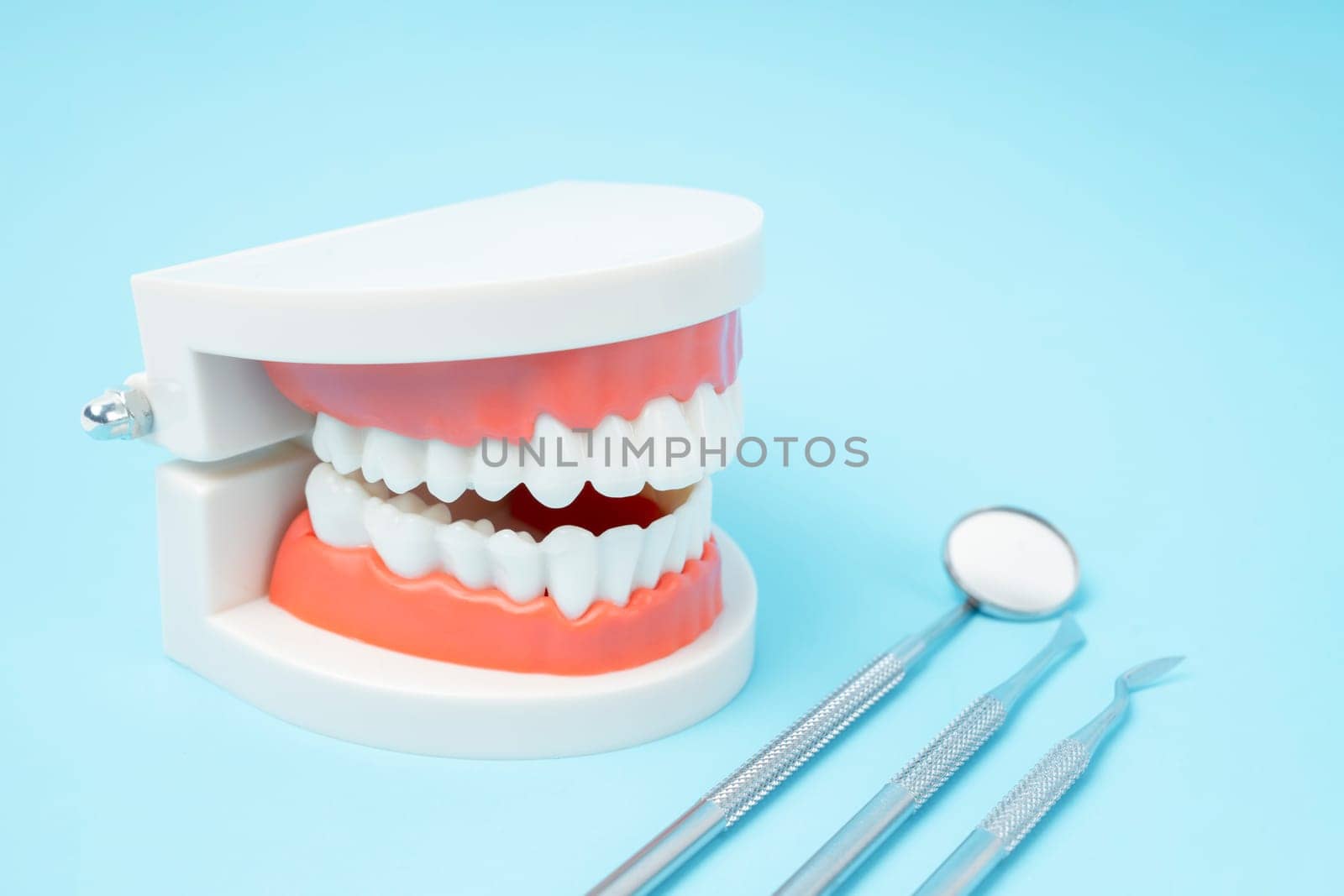 The Dentures model and instrument dental on blue background. by Gamjai