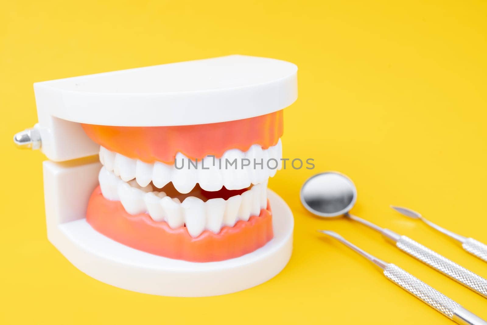 Dentures model and instrument dental on yellow background.