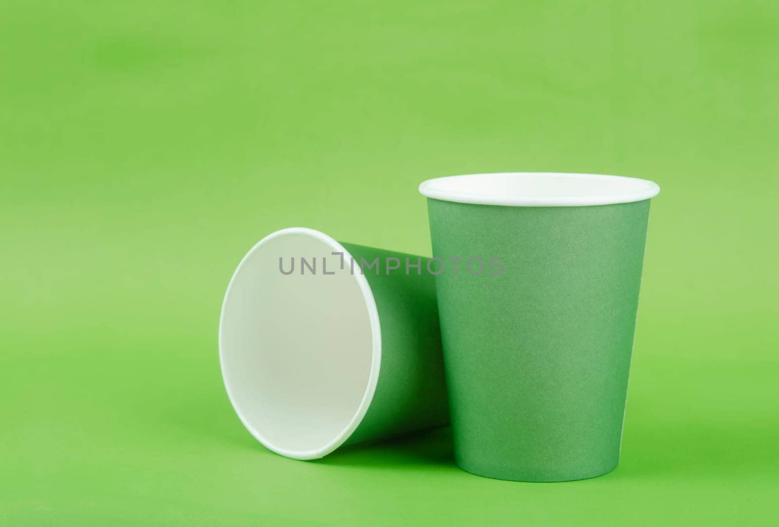 Green paper cup for takeaway on a green color background