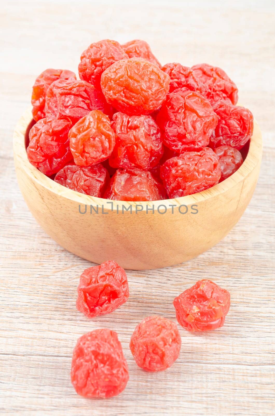 The Dried red prunes fruits (Preserved fruits Chinese plum) in wooden bowl on wooden background. by Gamjai