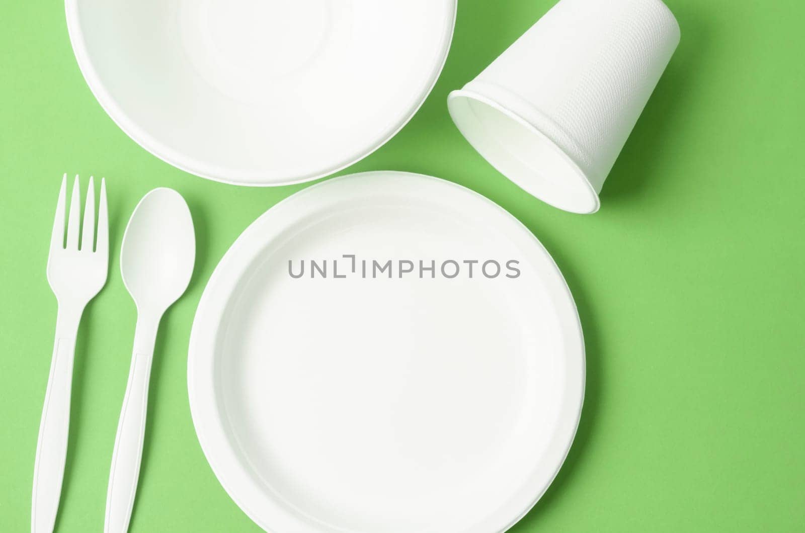 Eco friendly biodegradable paper disposable for packaging food and paper glass on green background.