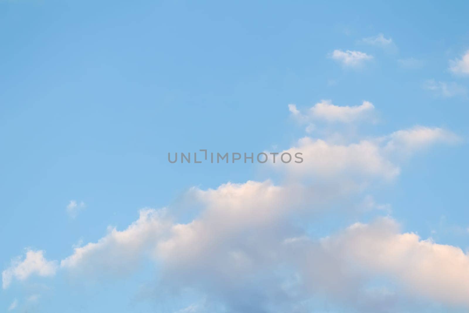 Background of blue sky with pale pink clouds at sunset