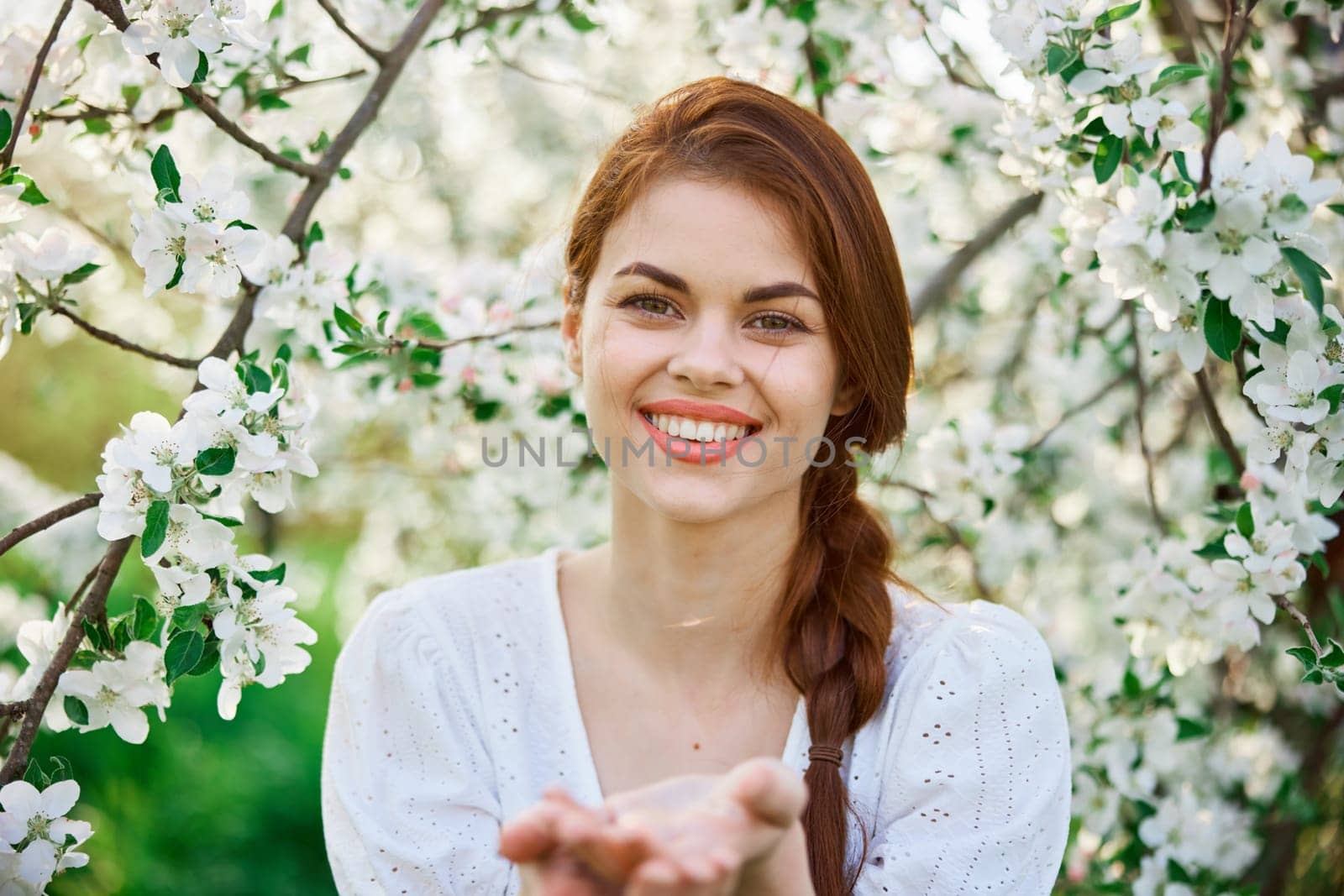 portrait of a happy, laughing red-haired woman next to a flowering tree in the garden. High quality photo