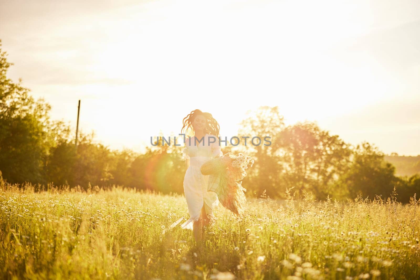 silhouette of a running woman in a light dress running across the field in the rays of the setting sun. High quality photo