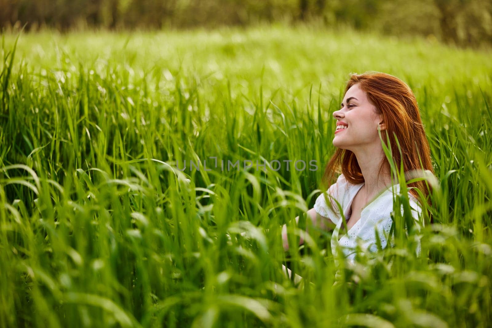 beautiful redhead woman relaxing sitting in tall grass. High quality photo
