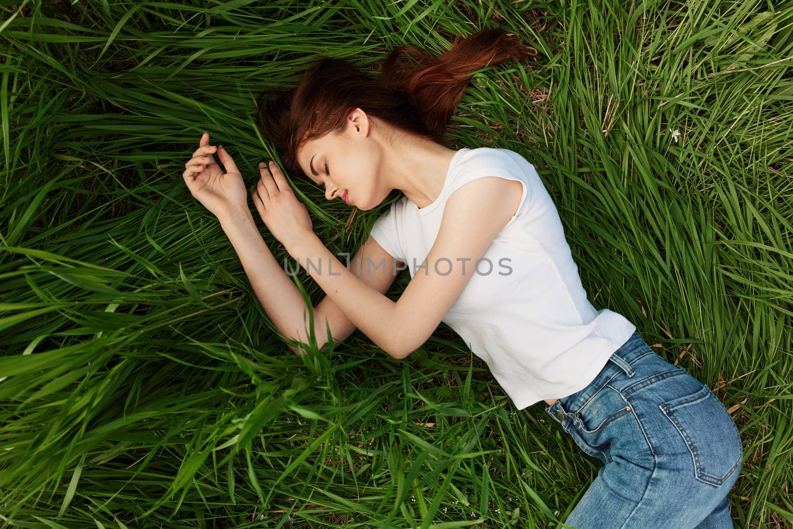 a peaceful woman lies in the grass enjoying the unity with nature. High quality photo