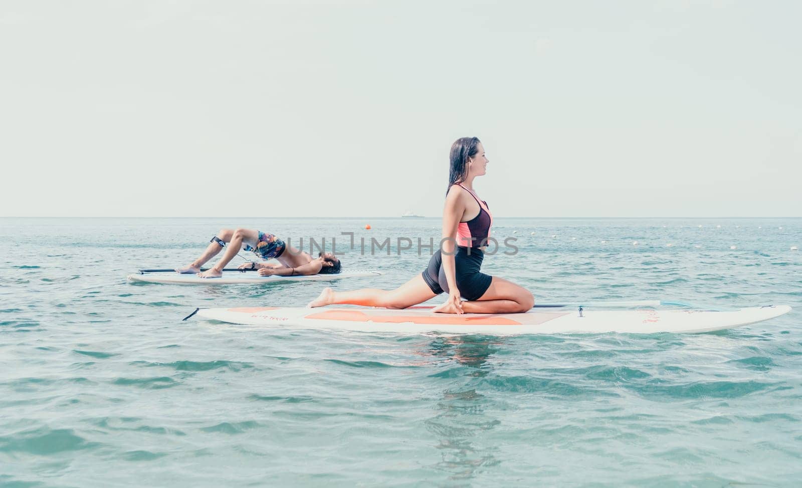 Woman sup yoga. Happy young sporty woman practising yoga pilates on paddle sup surfboard. Female stretching doing workout on sea water. Modern individual female outdoor summer sport activity. by panophotograph