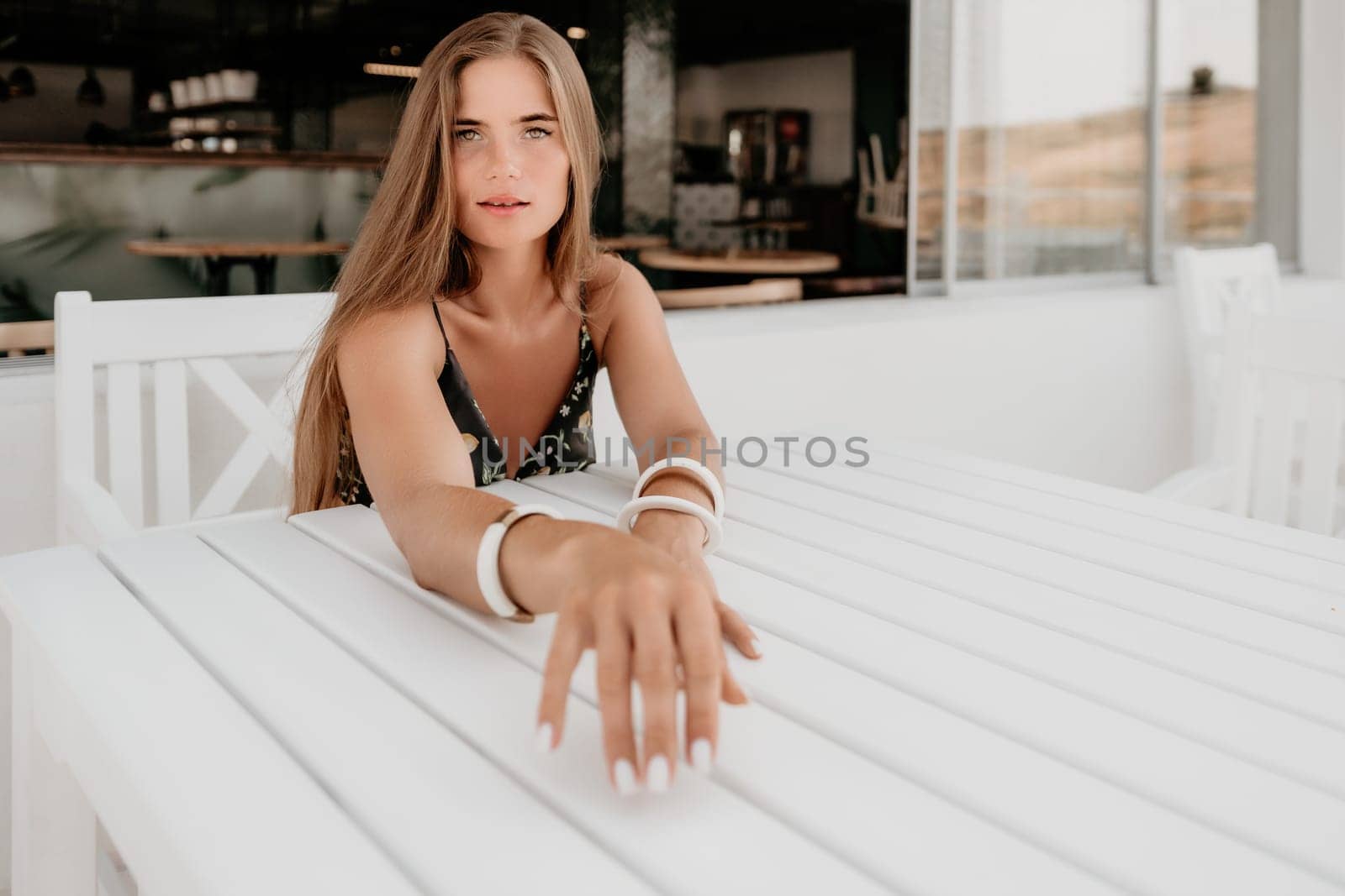 Happy woman portrait in cafe. Boho chic fashion style. Outdoor photo of young happy woman with long hair, sunny weather outdoors sitting in modern cafe