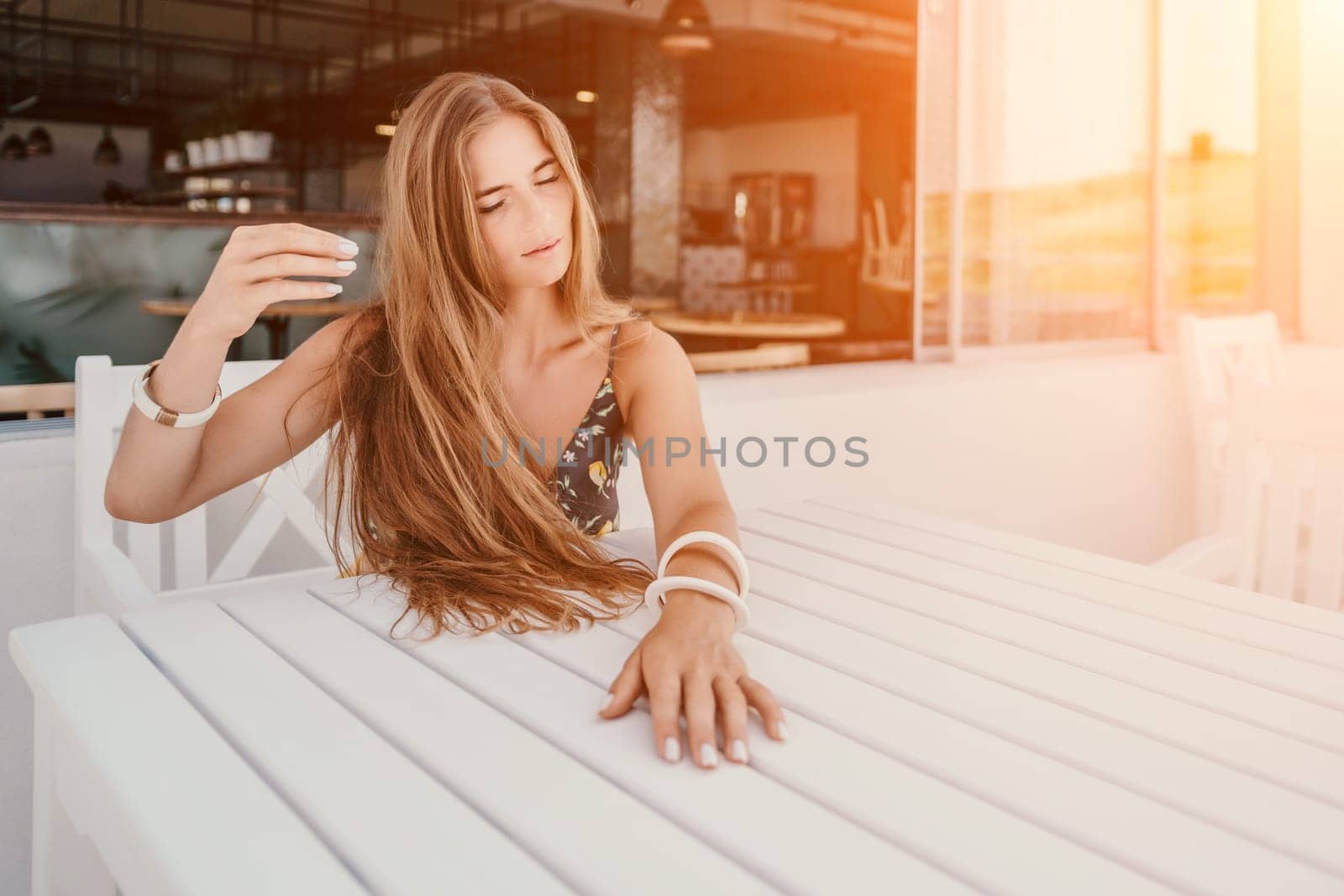 Happy woman portrait in cafe. Boho chic fashion style. Outdoor photo of young happy woman with long hair, sunny weather outdoors sitting in modern cafe