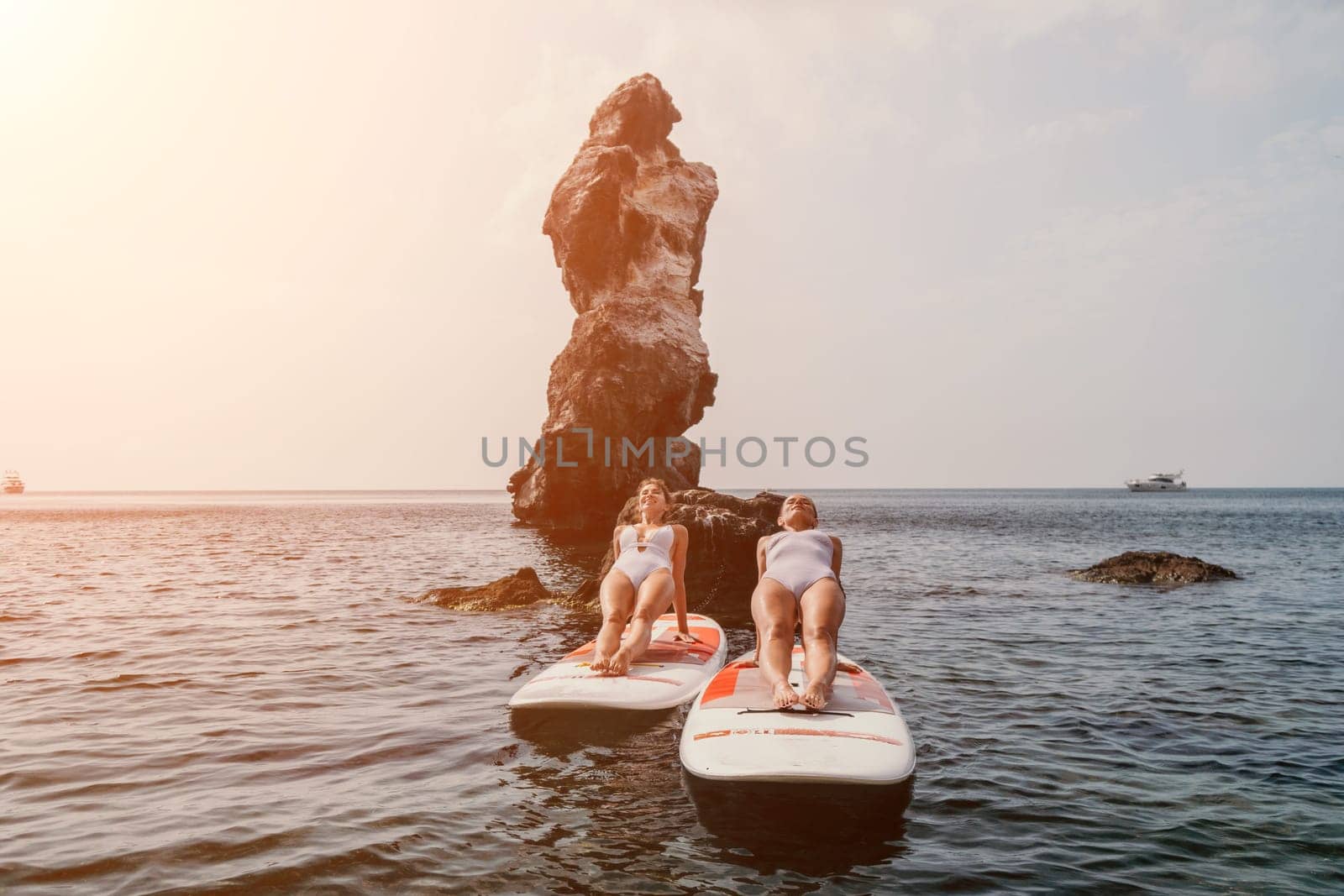 Woman sup yoga. Happy sporty woman practising yoga pilates on paddle sup surfboard. Female stretching doing workout on sea water. Modern individual female hipster outdoor summer sport activity. by panophotograph