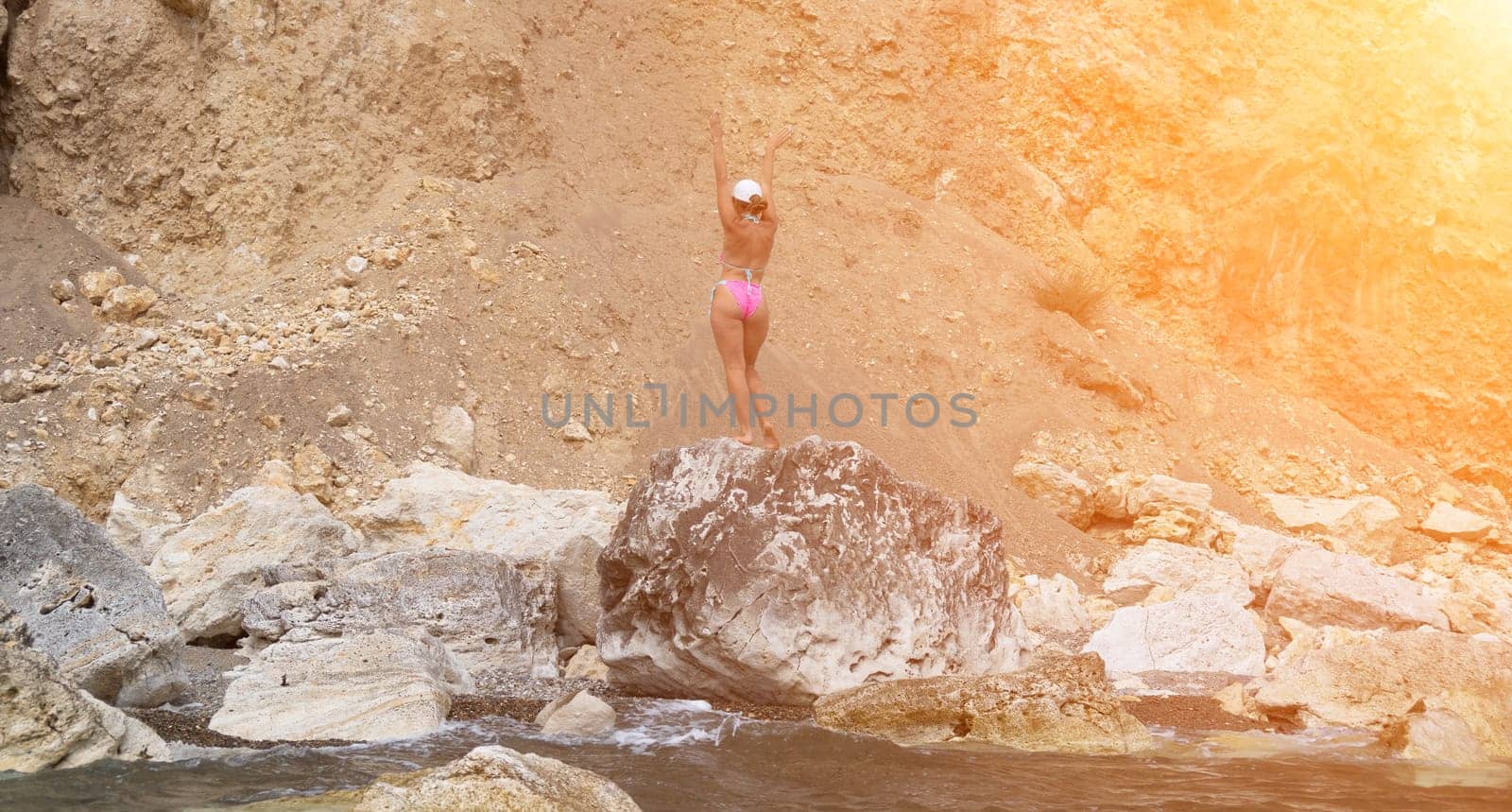 Woman travel sea. Young Happy woman in a long red dress posing on a beach near the sea on background of volcanic rocks, like in Iceland, sharing travel adventure journey