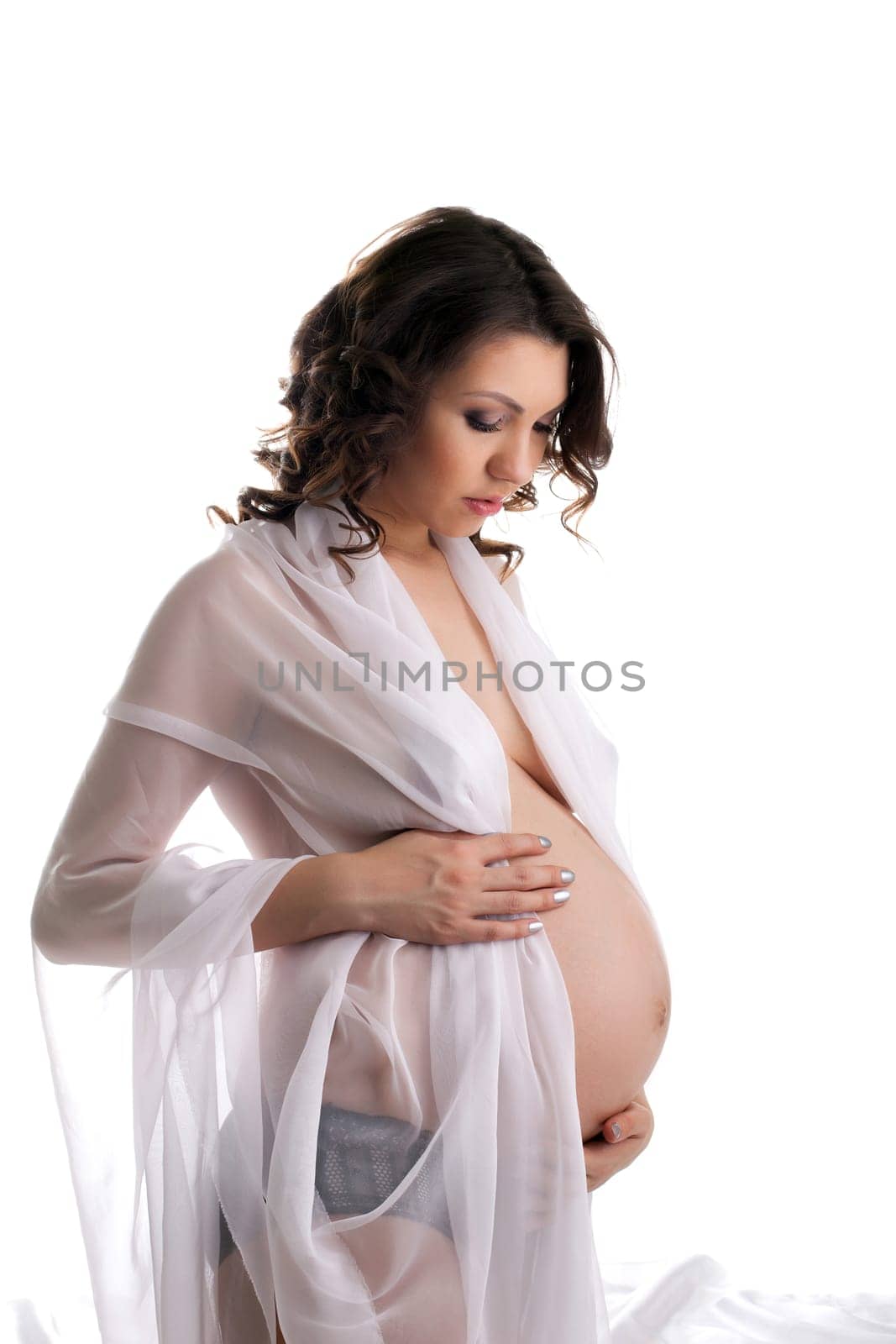 Charming pregnant woman posing stroking her belly, isolated on white