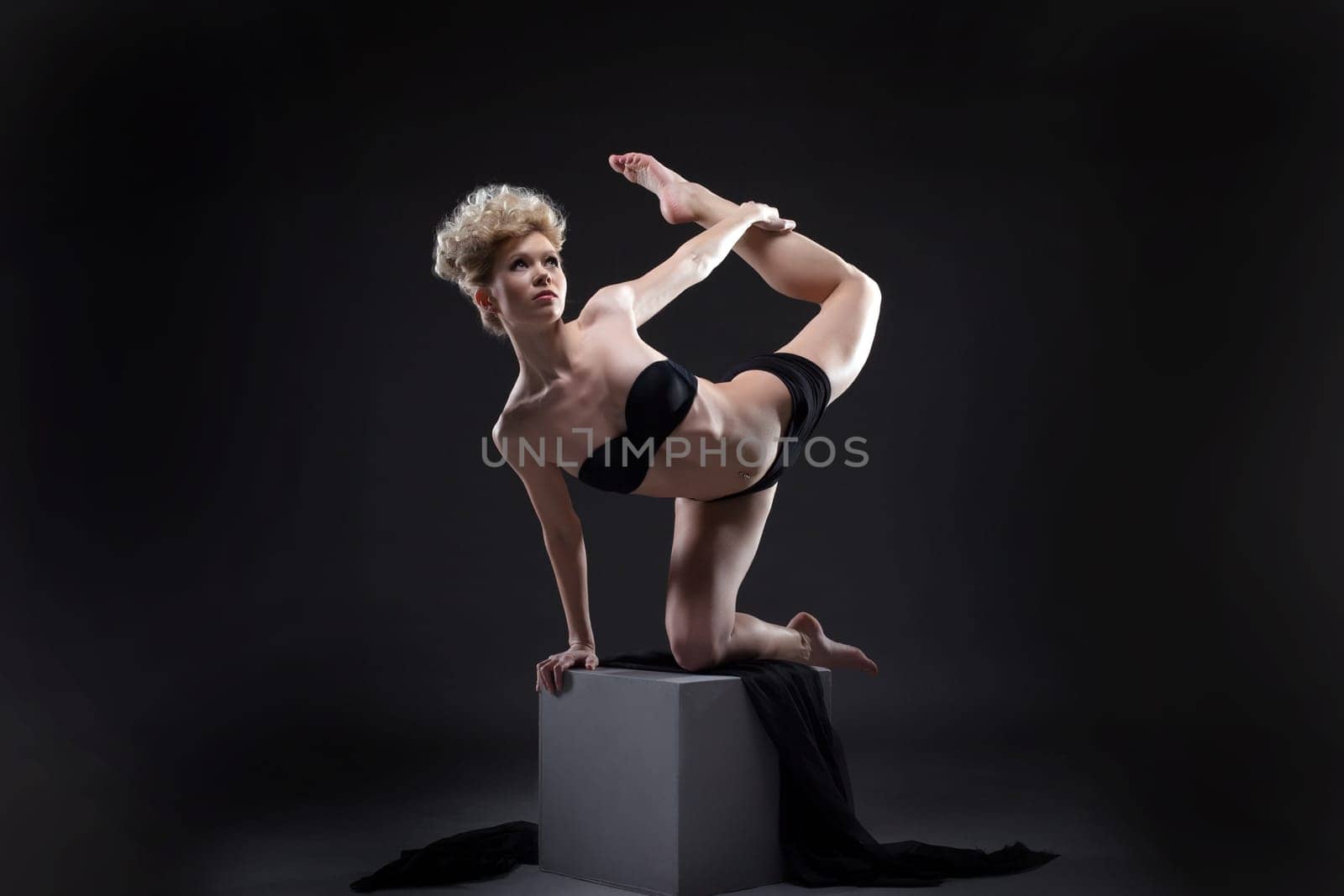 Studio shot of graceful young model dancing on cube