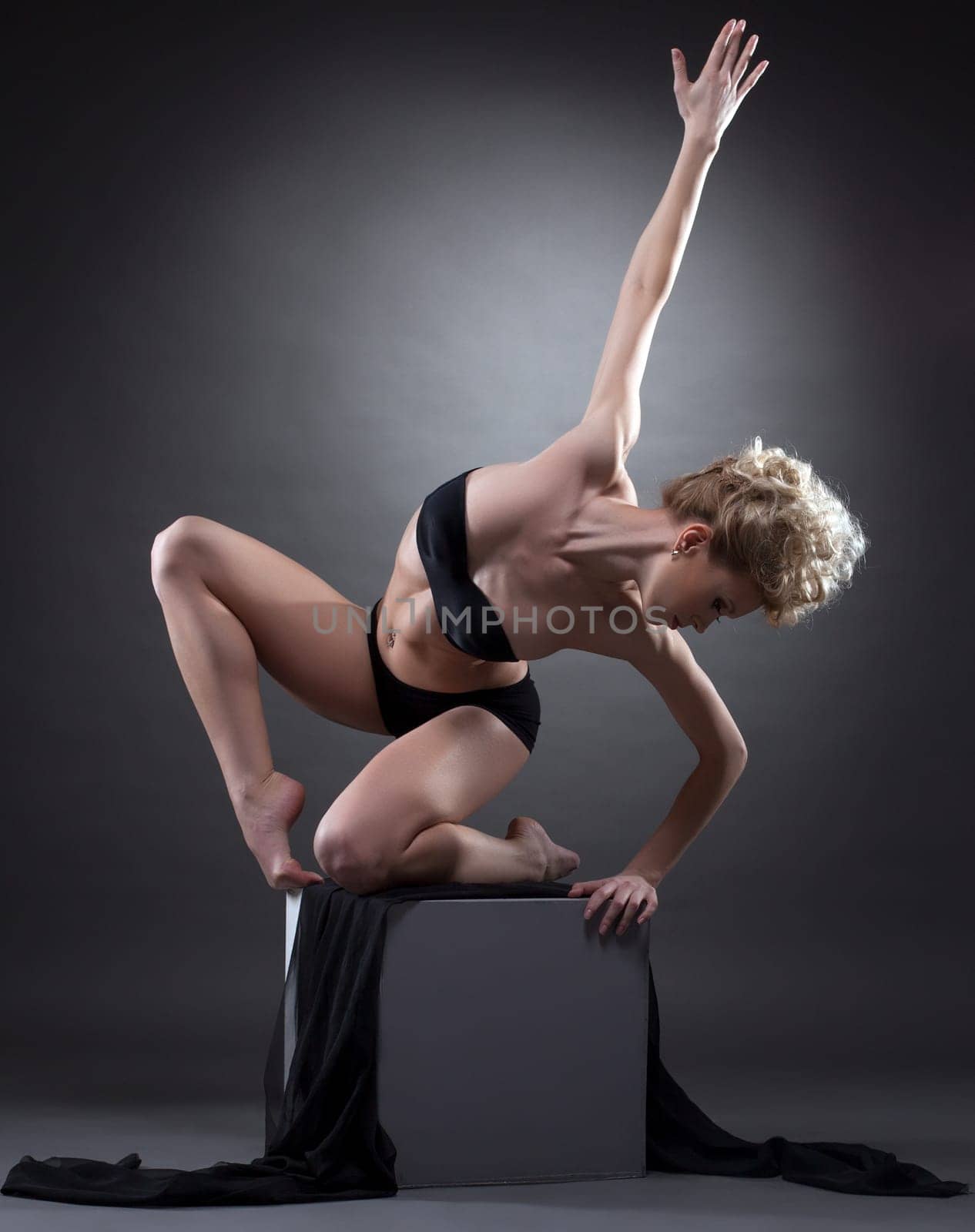 Image of beautiful graceful blonde dancing on cube in studio