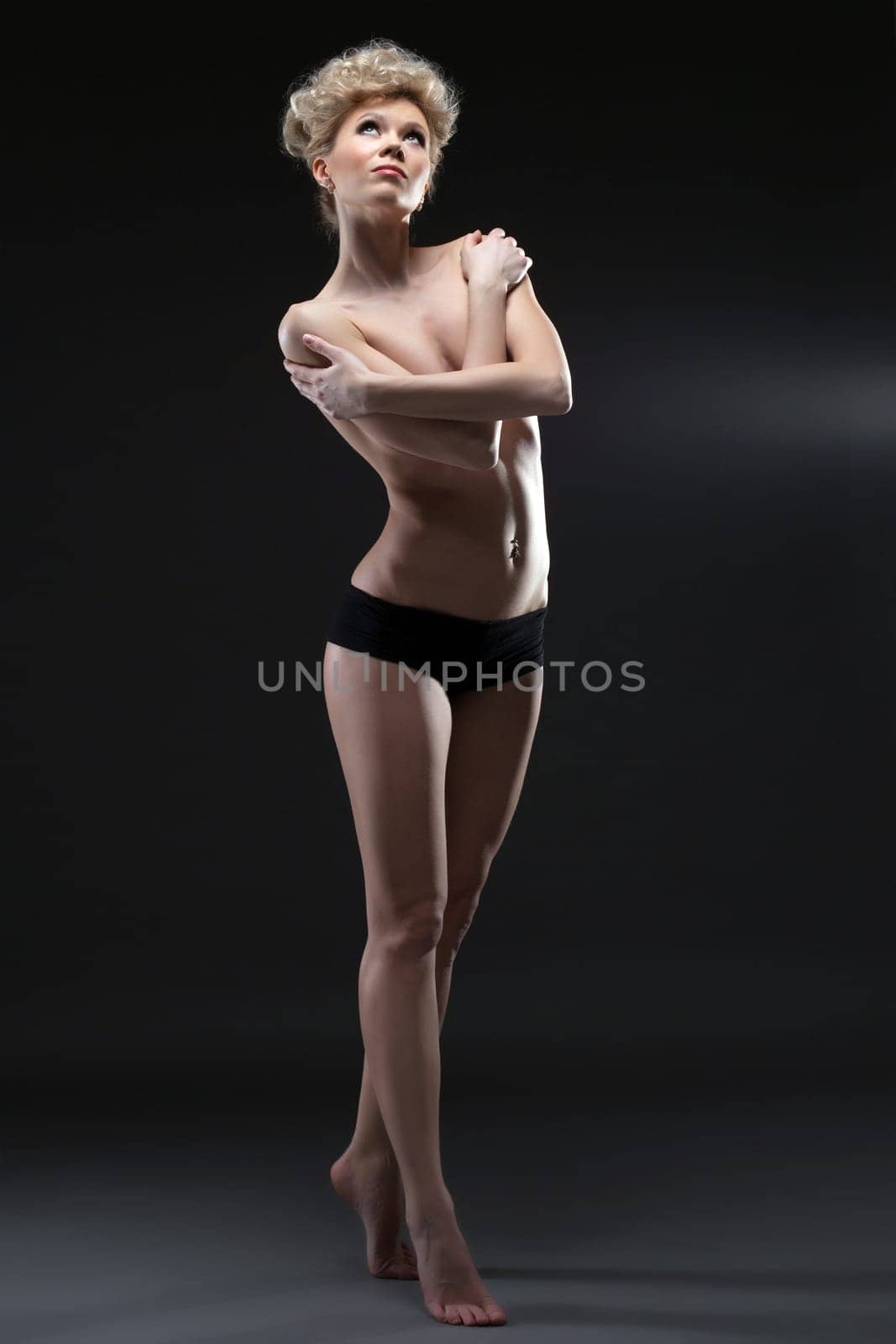 Image of lovely half-naked blonde posing in studio, on gray background