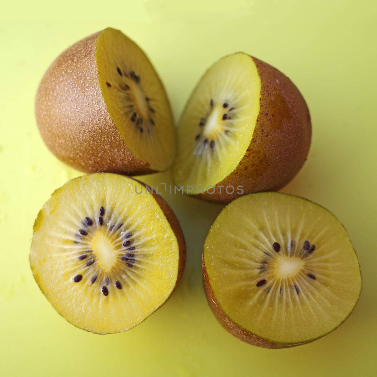 Two sliced ​​golden kiwis on a yellow cutting board