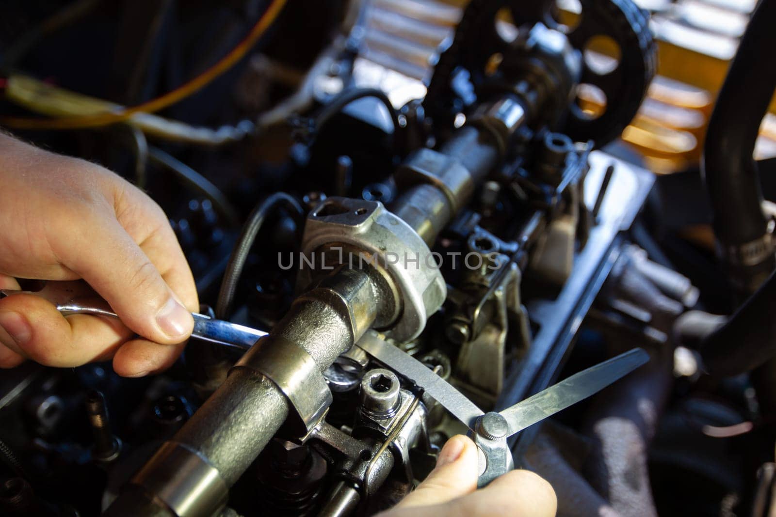 Mercedes diesel engine repair. Hands with a mechanic repairing Mercedes parts. Valve clearance adjustment. by Sviatlana