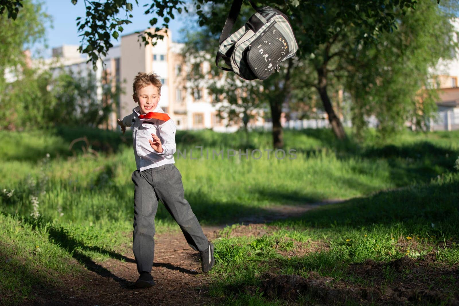 A happy schoolboy throws up his school backpack and rejoices at the start of the holidays. The end of the school year and the beginning of the holidays. by Sviatlana