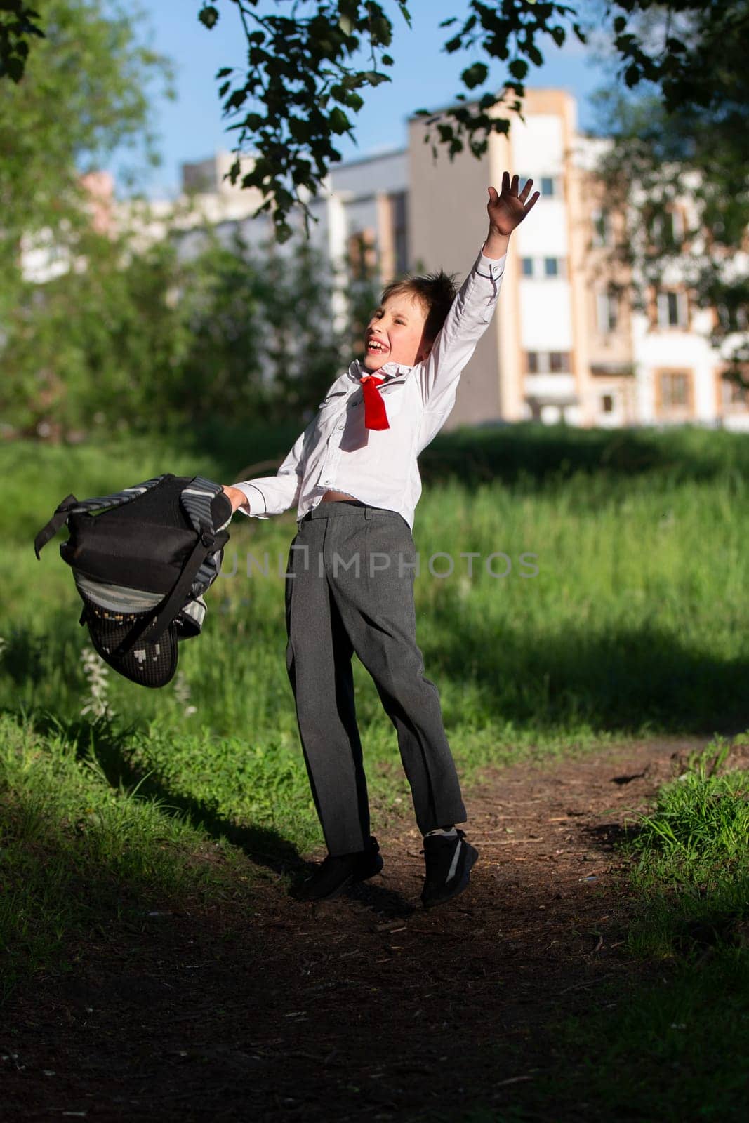 A happy schoolboy throws up his school backpack and rejoices at the start of the holidays. The end of the school year and the beginning of the holidays. by Sviatlana